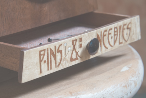 A photo of a wooden drawer with the words 'Pins & Neeles' written on it.
